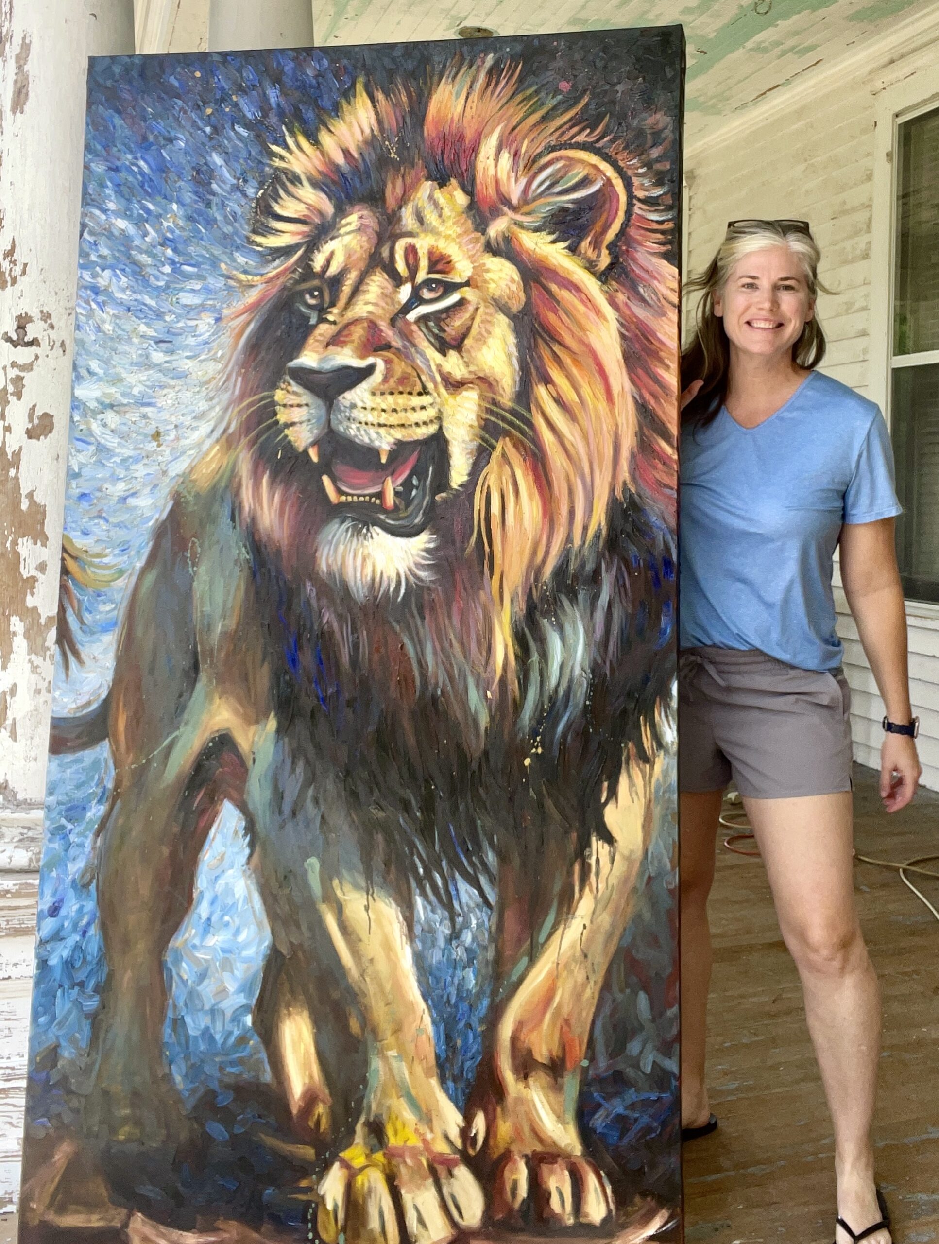Carol Ferguson holds up Original Oil painting of a giant lion painting